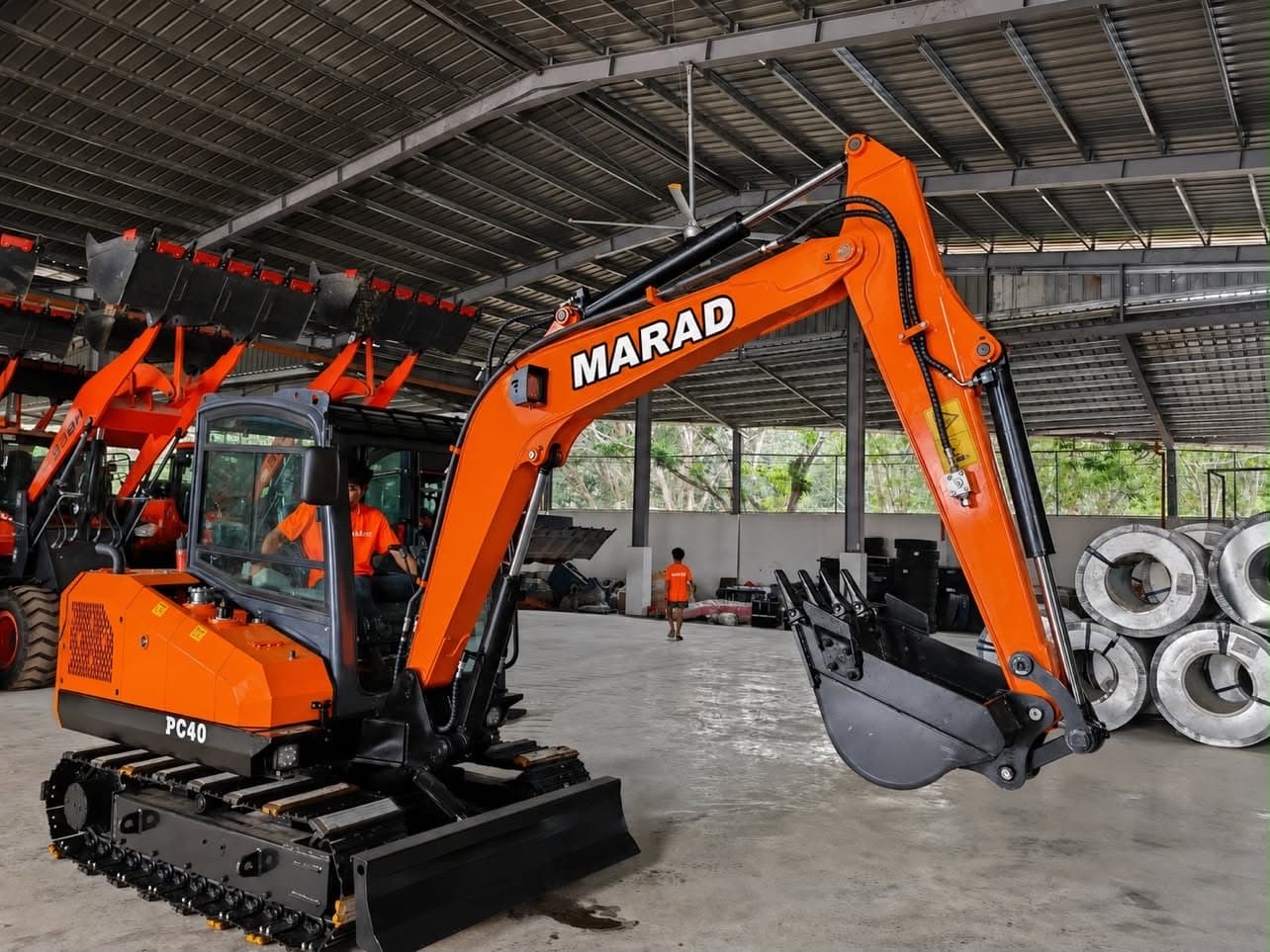 A MARAD PC40 mini excavator inside our Cavite warehouse, alongside other equipment and steel coil stock